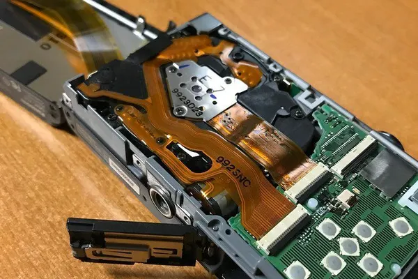 Compact camera opened up, showing the lens unit and circuit board