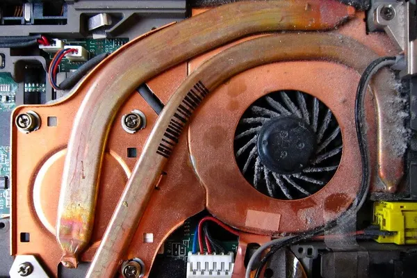 Inside a laptop: the cooling fan and copper heat pipe clogged with dust