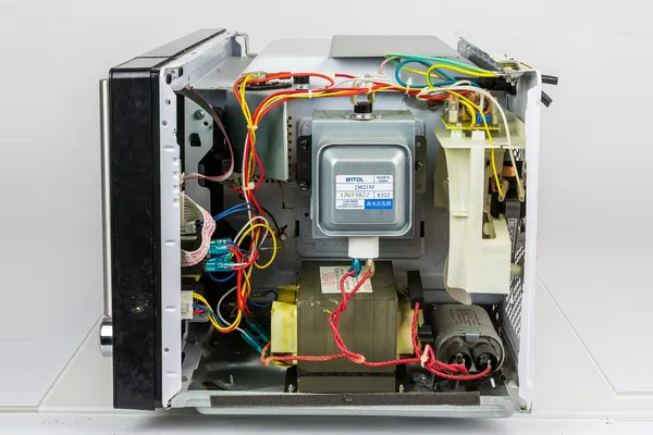 Microwave oven with the cover removed, showing the magnetron, transformer and wiring